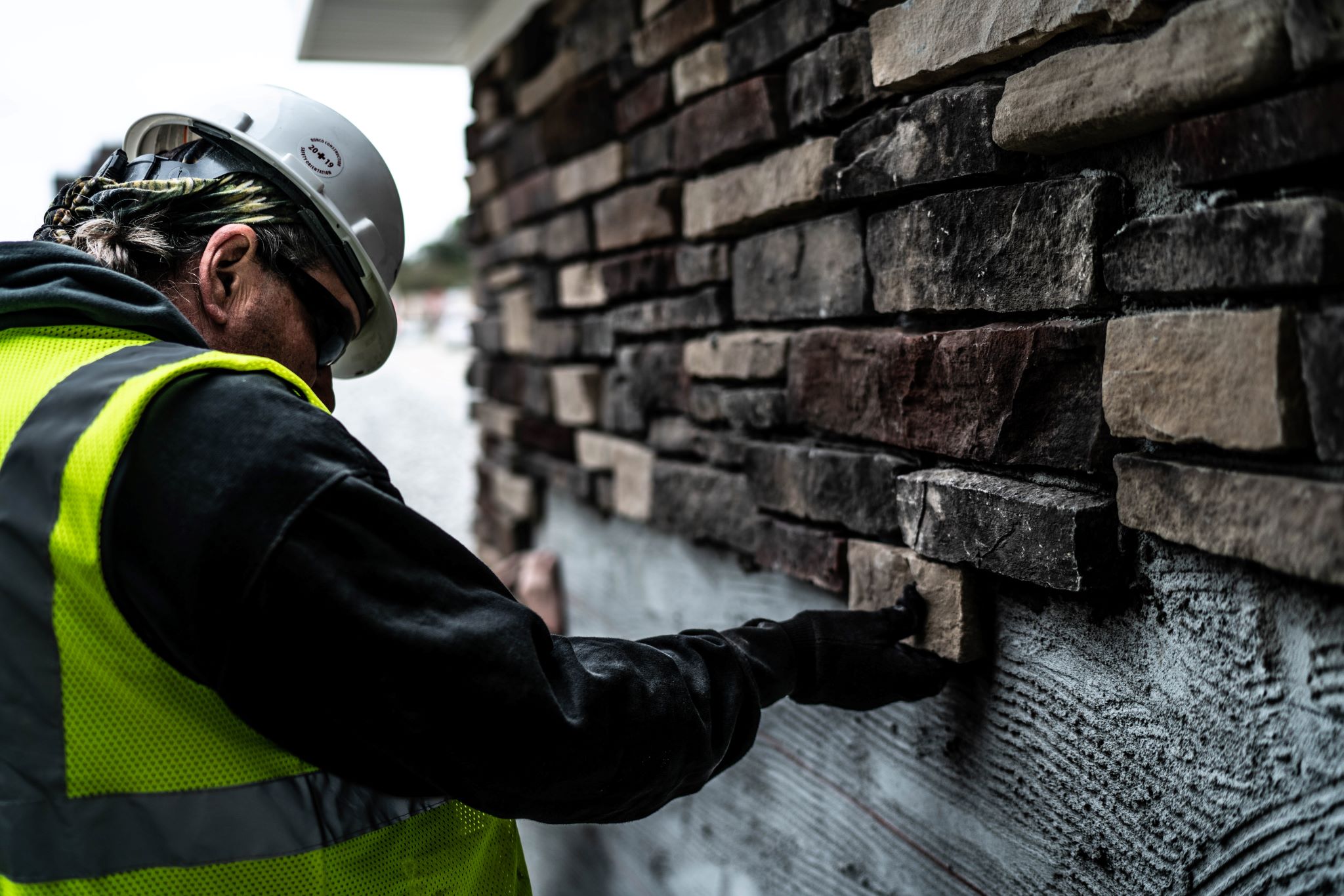 Construction worker completing a stone facade.